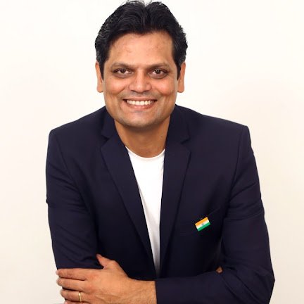 Vijay K. Banda smiling, in a navy blazer with a small Indian flag pin